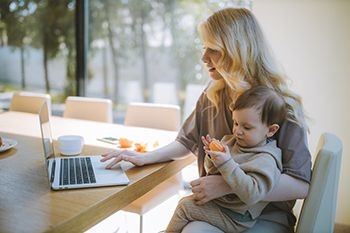 Woman-on-laptop-holding-child